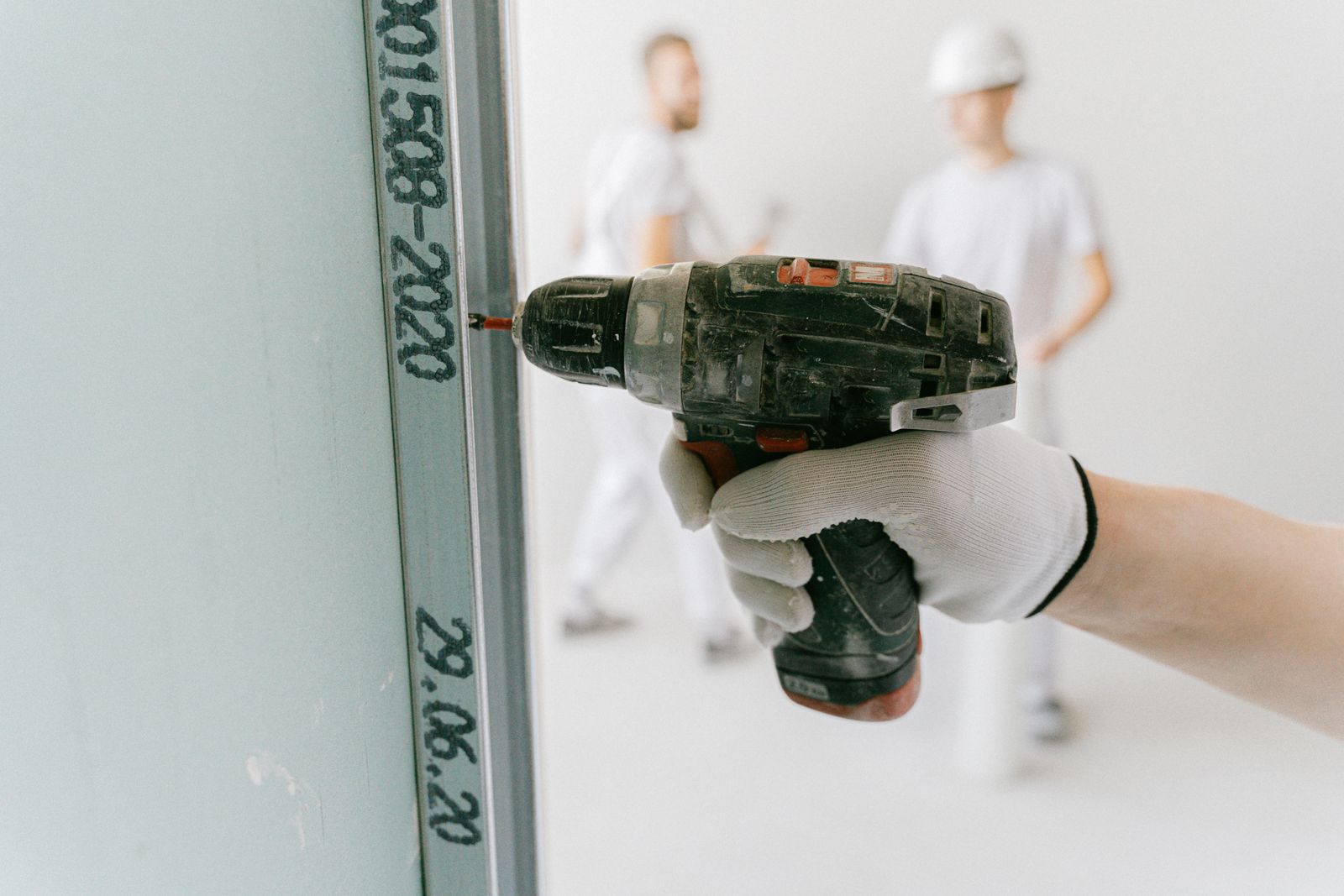 Montagem de divisória em drywall, placa sendo aparafusada no perfil